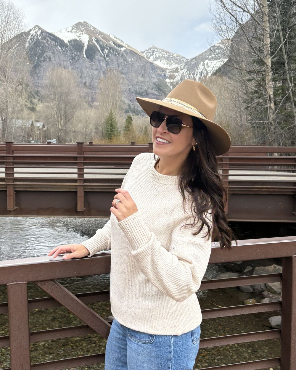A smiling woman wearing her finished camel hat outdoors